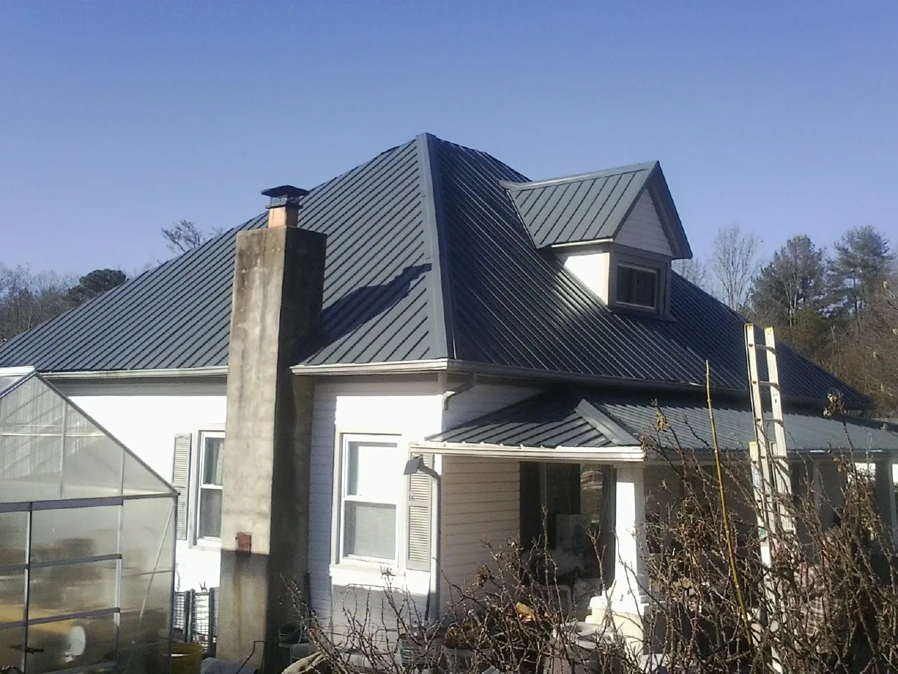 Dark blue standing seam metal roof on a white farmhouse with dormer — Slate & Tile Roof Repair by Roofing Brothers in Cades