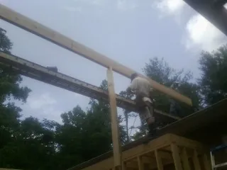 Carpenter setting a ridge beam over a new addition frame — Ice Dam Removal by Roofing Brothers in Cades