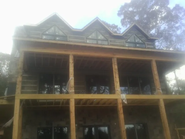 Dormers and porch framing on a large log home under construction — Roof Coating work by our crew in Cades