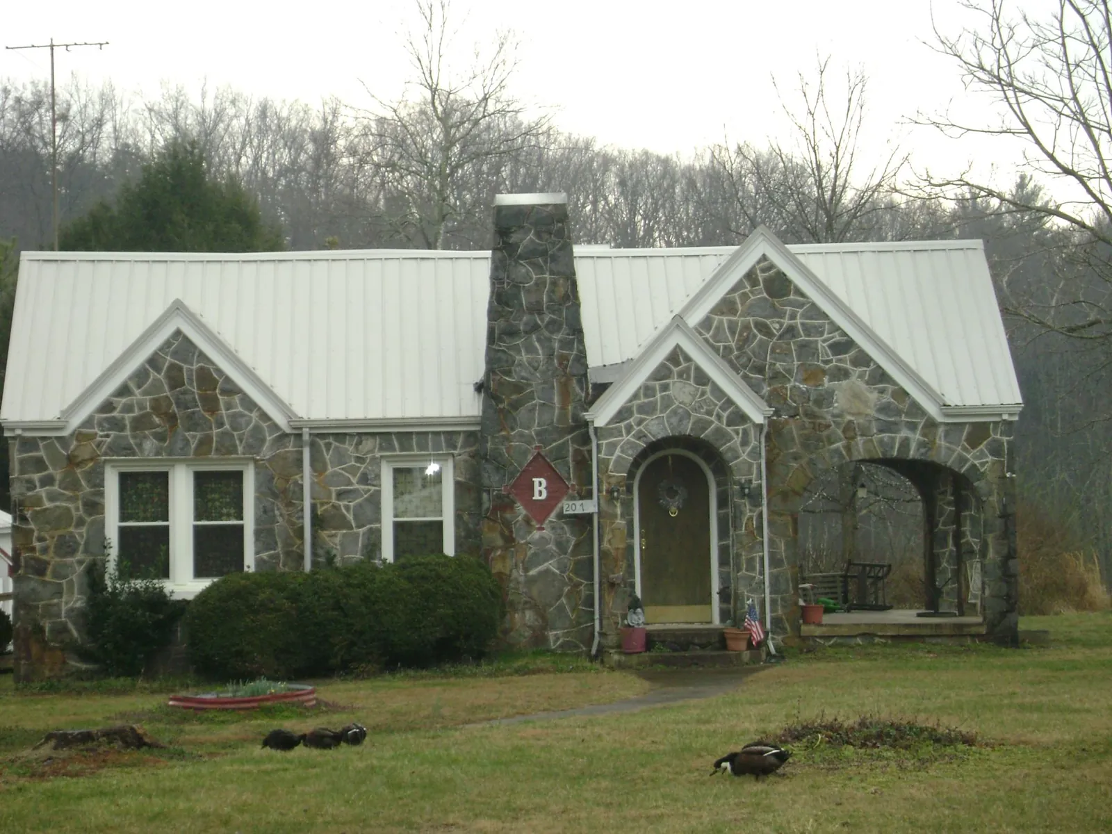 White metal roof on a stone cottage with steep gables in Cades