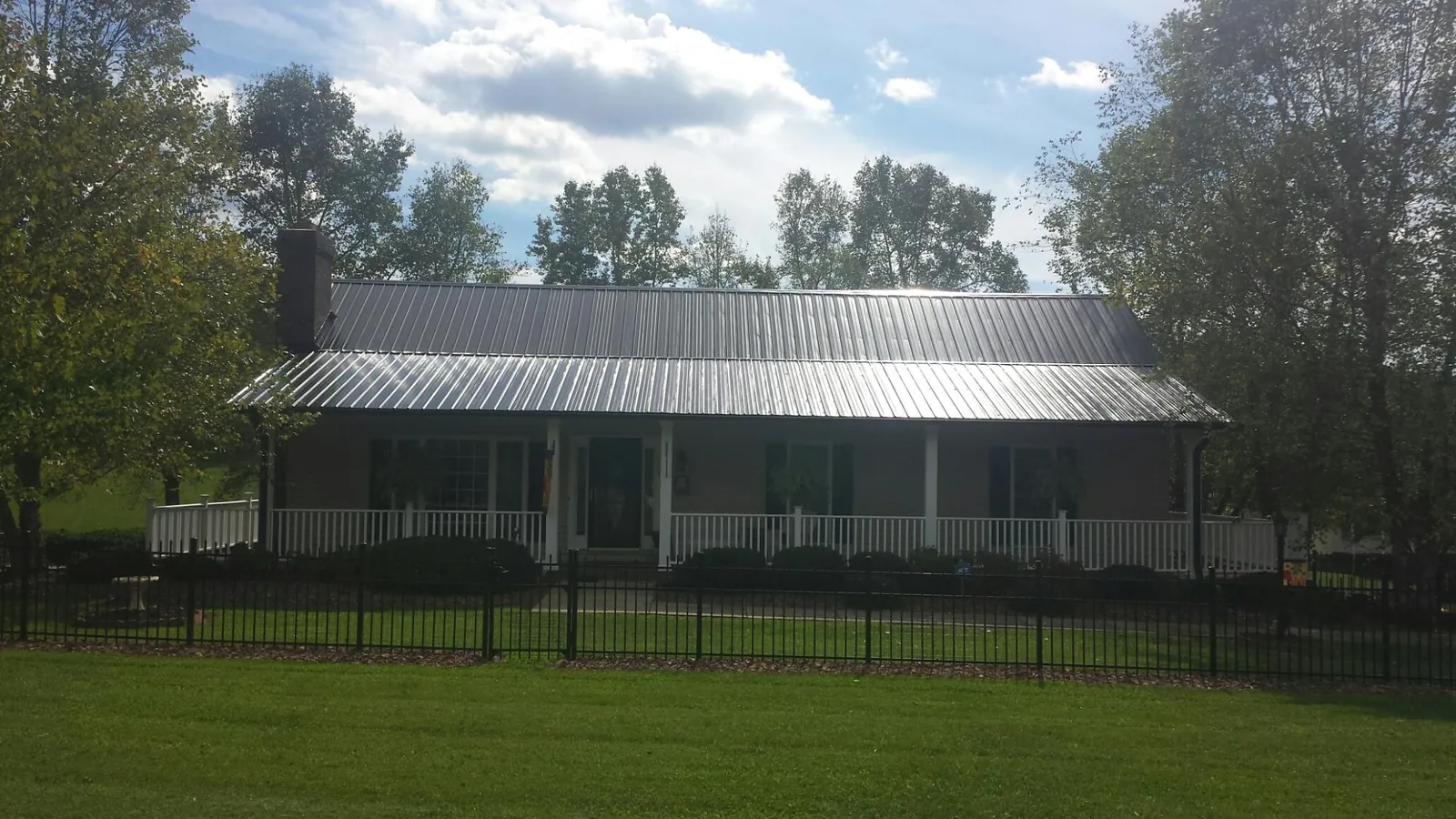 Gray metal roof on a brick ranch with a full width front porch — Gutter Guard Installation work by our crew in Cades