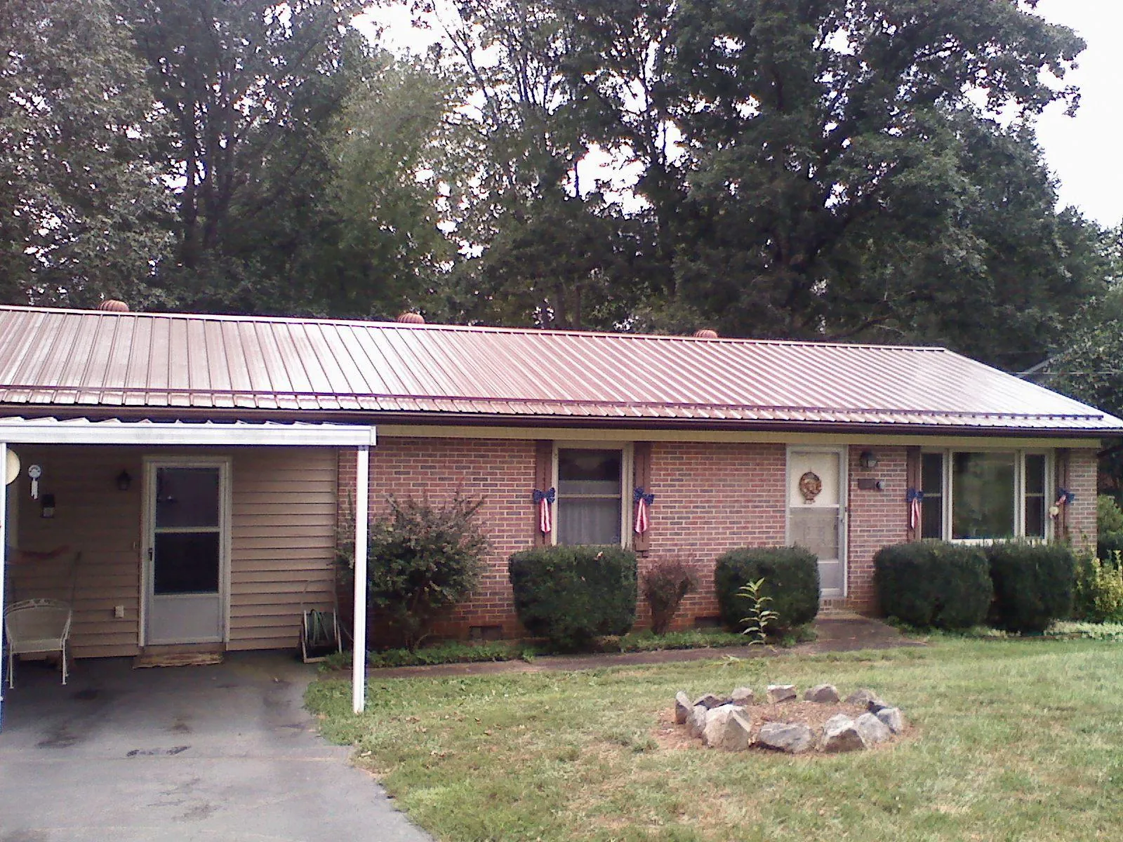 Bronze metal roof and carport on a brick ranch home — Roof Repair work by our crew in Cades